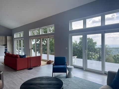 Bright living room with a red sofa, blue chair, and wide windows