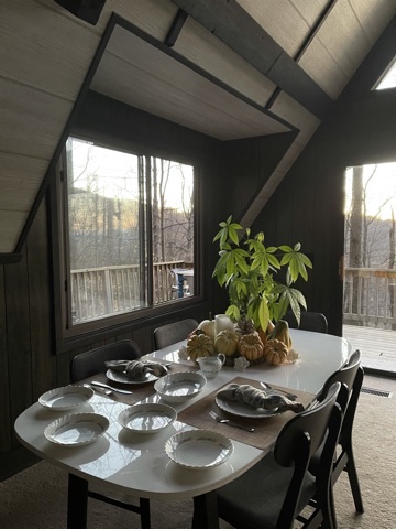 Thanksgiving table set in daylight, with a leafy centerpiece and a view through the windows